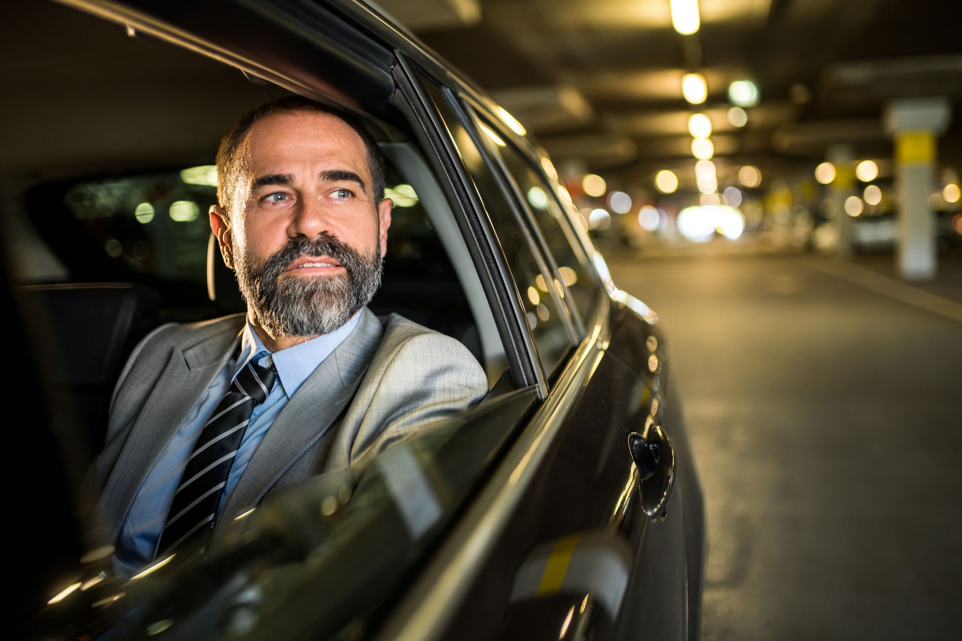 Happy mature businessman riding on backseat of a car.